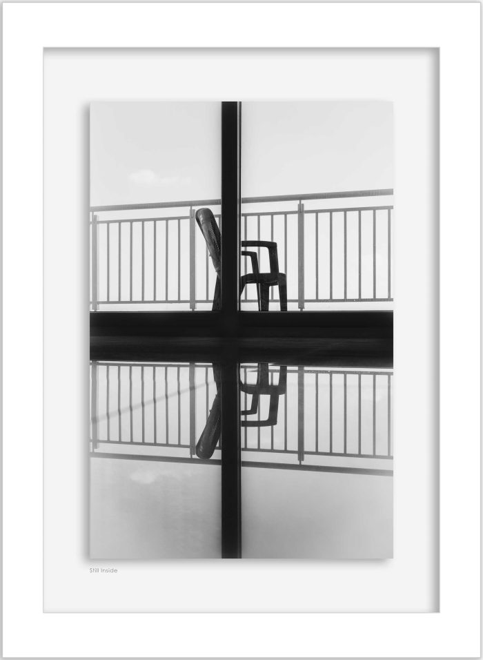 Framed black and white photograph of a chair with reflection displayed on a wall