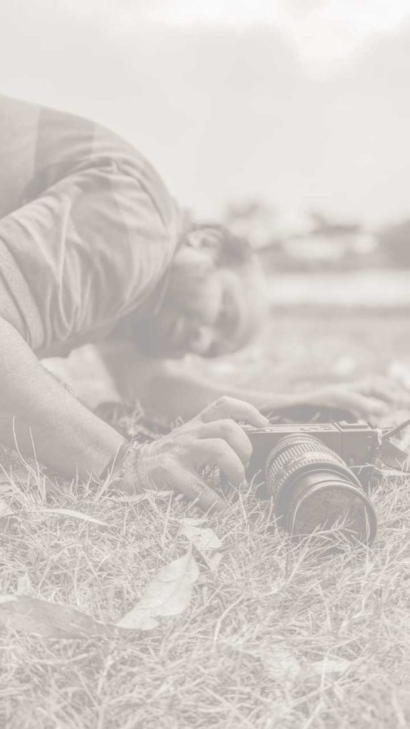 Photographer lying on grass adjusting camera outdoors